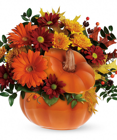 Ceramic pumpkin filled with orange, yellow and red fall flowers and leaf accents